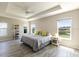 Inviting main bedroom with tray ceiling, ceiling fan, and large windows overlooking a serene view at 3334 Pierluissi Path, The Villages, FL 32163