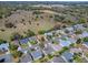 Overhead aerial image of a house adjacent to a broad, grassy area and verdant trees in a residential community at 337 Olanta Dr, The Villages, FL 32162