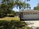 View of a two-car garage with a screened-in pool in the background and lush, green lawn at 36709 Sandy Ln, Grand Island, FL 32735