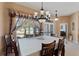 Formal dining room featuring elegant chandelier, window with decorative drapes, and seating for eight at 410 Majestic Gardens Blvd, Winter Haven, FL 33880