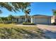 Charming single-story home featuring a well-manicured lawn, brick driveway, lush landscaping, and a two-car garage at 410 Majestic Gardens Blvd, Winter Haven, FL 33880