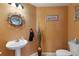 Stylish half bathroom features pedestal sink, decorative mirror and accents, and updated fixtures at 410 Majestic Gardens Blvd, Winter Haven, FL 33880