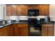 Well-equipped kitchen featuring wood cabinetry, granite countertops, and modern black appliances at 410 Majestic Gardens Blvd, Winter Haven, FL 33880