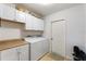 Bright laundry room with white cabinetry, washer, dryer and storage at 410 Majestic Gardens Blvd, Winter Haven, FL 33880