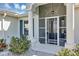 Inviting front porch with decorative columns, screened door, and neatly trimmed bushes at 4419 Clear Brook Ct, Leesburg, FL 34748