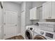 Well-equipped laundry room with modern washer and dryer, plus storage cabinets at 4419 Clear Brook Ct, Leesburg, FL 34748