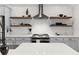 Modern kitchen showcasing white subway tile, floating shelves, and stainless steel hood at 4521 Whittingtin Circle, The Villages, FL 32163