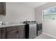 Bright laundry room features modern washer and dryer, gray cabinets, and white countertops at 4521 Whittingtin Circle, The Villages, FL 32163