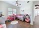 Bright bedroom with a ceiling fan, wood floors, and a pink princess themed decor at 464 Long & Winding Rd, Groveland, FL 34736
