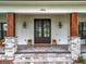 Close-up of a home's front porch featuring stone columns, a modern double door, and charming decor at 464 Long & Winding Rd, Groveland, FL 34736
