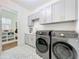 Well-lit laundry room with modern appliances, stylish cabinets, and patterned tile flooring at 464 Long & Winding Rd, Groveland, FL 34736