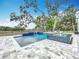 Stunning pool with a waterfall feature and lounge chairs surrounded by large, mature oak trees at 464 Long & Winding Rd, Groveland, FL 34736