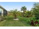 The backyard showcases lush landscaping, featuring several palm trees, shrubs, and green lawn at 5510 Thome Loop, The Villages, FL 32163