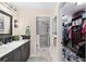 Modern bathroom featuring a marble vanity, walk-in shower, and an open closet with custom shelving at 5510 Thome Loop, The Villages, FL 32163