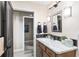 Well-lit bathroom featuring a wood vanity with marble counters and a shower in the next room at 5510 Thome Loop, The Villages, FL 32163