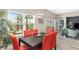 Sunlit dining area with sliding glass doors, red chairs, and view to the lanai at 5510 Thome Loop, The Villages, FL 32163