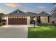 Charming single-story home with a well-lit lawn and a two-car garage at twilight at 5510 Thome Loop, The Villages, FL 32163