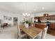 This bright dining room features a wooden table, an elegant chandelier, and a kitchen area with stainless steel appliances at 5675 Herman Ave, The Villages, FL 32163