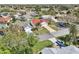 Neighborhood aerial view showcasing a home with a vibrant red roof nestled amongst lush greenery and a nearby golf course at 750 Evelynton Loop, The Villages, FL 32162