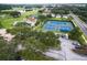 Vibrant aerial view of a community with tennis courts, swimming pool, and lush greenery at 8051 Saint James Way, Mount Dora, FL 32757