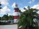 Scenic view of a red and white striped lighthouse near the water and tropical palm trees at 8051 Saint James Way, Mount Dora, FL 32757