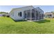 View of the home's back exterior, including a screened in patio, with green grass and a trimmed lawn at 841 Eagles Lndg, Leesburg, FL 34748