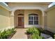 Inviting entryway with a wood door, arched window, and manicured landscaping at 859 Parksville Path, The Villages, FL 32162