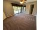 This carpeted bedroom features sliding glass doors to a balcony and mirrored closet doors at 1000 Royal Oak Blvd, Leesburg, FL 34748
