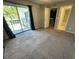 Carpeted bedroom with sliding glass doors lead to a balcony that overlooks lush tropical foliage at 1000 Royal Oak Blvd, Leesburg, FL 34748