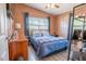 Bedroom with cozy blue bedding, wood floors, dark curtains, and modern dresser at 102 S Sunland Dr, Sanford, FL 32773