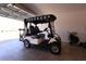 Garage featuring a white golf cart with plush, black leather seating, ready for leisurely rides around the neighborhood at 1435 Jeremy Cir, The Villages, FL 34762