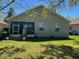 Exterior view of backyard with a covered porch, shutters, and green lawn at 155 Crepe Myrtle Dr, Groveland, FL 34736