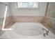 Luxurious bathtub featuring marble surround, brushed nickel hardware, and a large window for natural light at 15803 Fairview Pt, Tavares, FL 32778