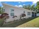 Tan home exterior featuring lush lawn, garden bed, and screened-in patio in a tranquil setting at 15803 Fairview Pt, Tavares, FL 32778