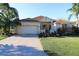 Inviting single-Gathering home with a paved driveway, mature landscaping, and a two-car garage at 1721 Carrera Dr, The Villages, FL 32159