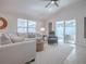 Bright living room features a sectional sofa, accent chair, ceiling fan, and access to the enclosed lanai at 1829 Foxwood Ln, The Villages, FL 32162
