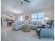 Spacious living room with natural light features a sectional sofa, accent chair, and access to the dining area at 1829 Foxwood Ln, The Villages, FL 32162