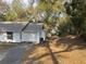 Exterior view of a charming home nestled among trees, featuring a driveway and garage at 1903 Lake Ella Rd, Fruitland Park, FL 34731