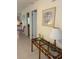 Hallway with a glass and rattan console table below framed art and a glimpse of another room at 1903 Lake Ella Rd, Fruitland Park, FL 34731