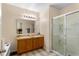 A spacious bathroom features a double vanity with wood cabinets and a glass-enclosed shower at 202 Compass Rose Dr, Groveland, FL 34736