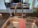 A stainless steel kitchen sink has a modern faucet with views into the living and dining room at 202 Compass Rose Dr, Groveland, FL 34736