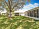 Manicured backyard featuring lush green grass, mature trees, and an enclosed sunroom at 25239 River Crest Dr, Leesburg, FL 34748