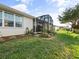 Well-maintained backyard featuring a screened lanai, manicured lawn, and tasteful landscaping for outdoor enjoyment at 5953 Sailboat Ave, Tavares, FL 32778