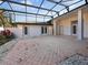 A screened patio featuring white walls, double doors, pavers, and a black metal frame, creating a private outdoor space at 5953 Sailboat Ave, Tavares, FL 32778