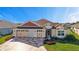 Charming home featuring a three-car garage, landscaped front yard, and beautiful color-coordinated stone driveway at 6126 Mulligan Run, The Villages, FL 32163