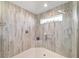 Beautifully tiled walk-in shower boasts a glass door, rainfall shower head, and a small window for natural light at 6126 Mulligan Run, The Villages, FL 32163