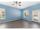 Bedroom with neutral blue walls, hardwood floors, a ceiling fan, and natural light at 6200 Topsail Rd, Lady Lake, FL 32159