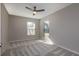 Neutral bedroom with light-colored carpet, three windows, and a ceiling fan at 7549 Frog Log Ln, Leesburg, FL 34748