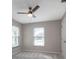 Neutral bedroom with a ceiling fan, two windows, and a white door on the right at 7549 Frog Log Ln, Leesburg, FL 34748