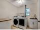 Bright laundry room featuring white washer and dryer, sink, cabinet, and neutral tones at 7549 Frog Log Ln, Leesburg, FL 34748